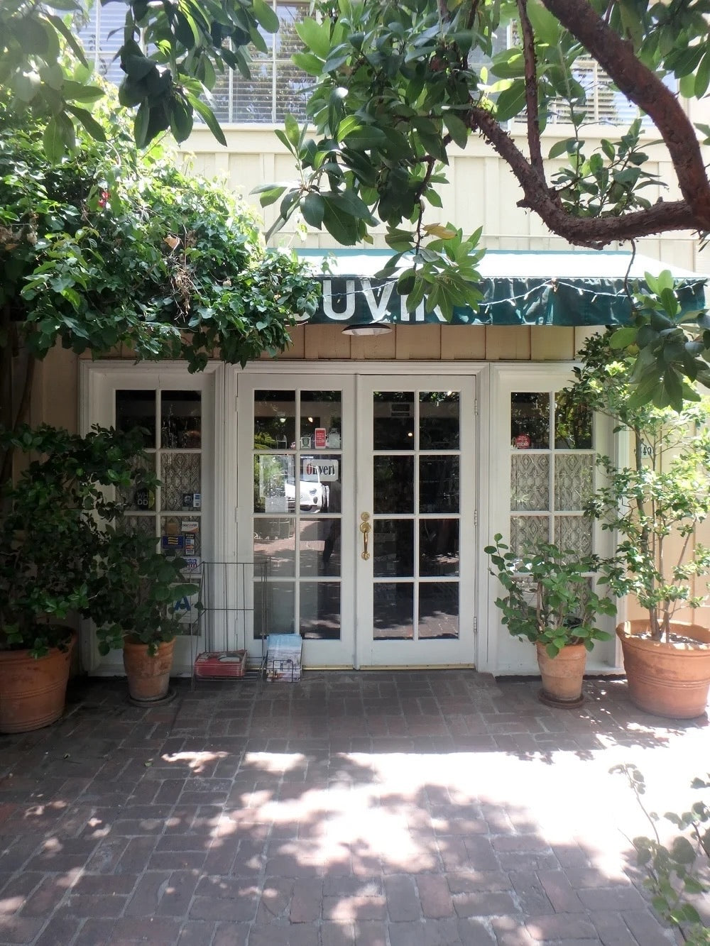 Ivy-covered Du Vin entrance with a green awning and French doors in West Hollywood.